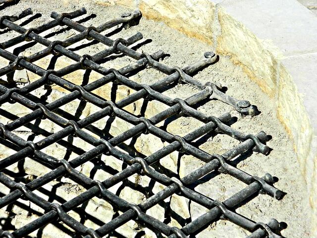 Datei:Geschmiedetes Brunnengitter wechselseitige Kreuzlochung Detail Mauernägel.jpg
