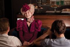 Effie acompañando a Peeta y Katniss.jpg